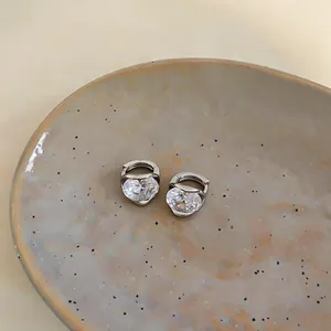 Dettaglio di orecchini minimalisti in argento con scintillanti zirconi a forma di cuore.