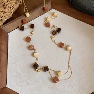 Dettaglio della collana bohémien a doppio strato con perle in resina color ambra e crema