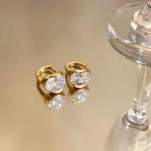 Primo piano di orecchini a cerchio placcati oro 18 carati con pietre di zircone ovali.