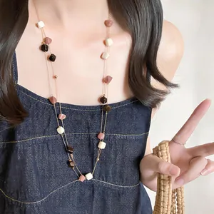 Dettaglio di una collana bohémien a due strati con pietre colorate su una modella.