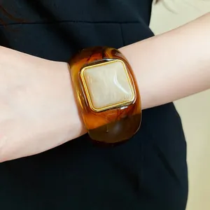 Wide amber acrylic bangle with a gradient finish and a square marble inlay on a wrist