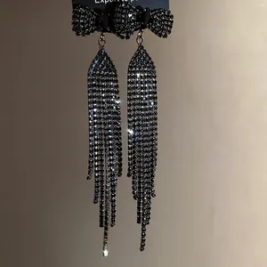Close-up of black rhinestone bow tassel earrings with sparkling fringe details