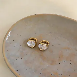 Dettaglio ravvicinato di orecchini huggie placcati in oro 18k con zircone ovale in stile francese