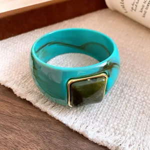 Detail view of the dark green square inlay on a teal marbled acrylic bangle.