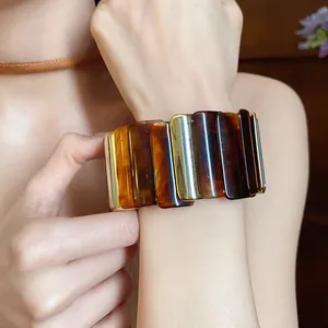 Vista dettagliata di un ampio bracciale in acrilico con finiture tartarugate e metalliche