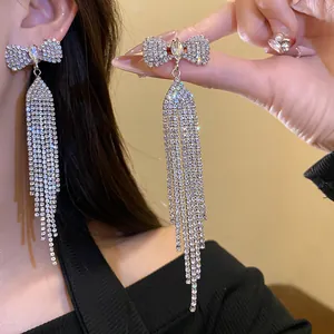 Detailed close-up of elegant rhinestone bow tassel earrings showing sparkling diamond details.
