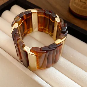 Primo piano del bracciale in acrilico ambra stile Maillard con inserti in metallo oro