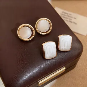 French style minimalist geometric gold stud earrings with white pearlescent inlay on leather box