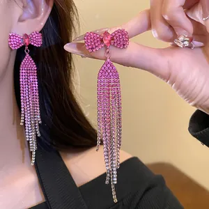 Detail view of pink rhinestone bow earrings with long sparkling crystal tassels
