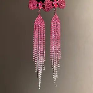 Close-up of pink rhinestone bow tassel earrings with sparkling gradient details
