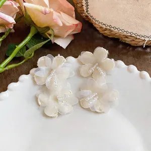 Detailed macro shot of elegant white chiffon flower earrings with delicate glass beads