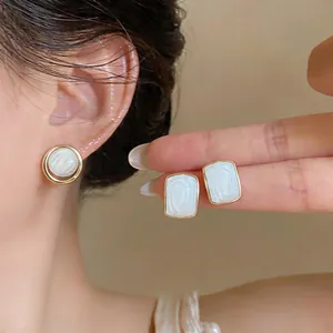 Detailed view of elegant white geometric stud earrings with gold-toned minimalist borders