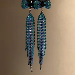 Detailed view of silver needle bow knot tassel earrings with blue and green rhinestones