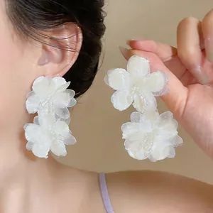 Close-up detail of white chiffon flower earrings with delicate glass bead accents
