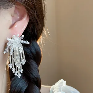 Detailed view of elegant glass flower tassel clip-on earrings on an Asian model