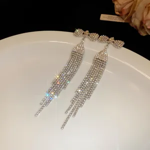 Detailed macro view of sparkling rhinestone bow tassel earrings with elegant silver needles