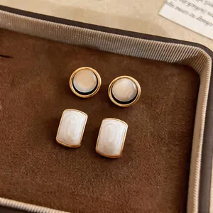 Close-up of elegant French style round and rectangular stud earrings inside a jewelry tray