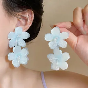 Detail view of light blue chiffon flower earrings with delicate glass beads
