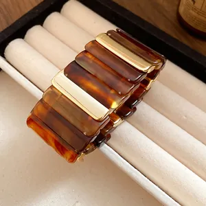 Dettaglio di un bracciale vintage in acrilico tartarugato con accenti dorati.