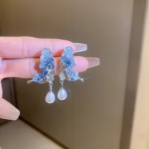 Exquisite blue crystal butterfly stud earrings featuring a white teardrop pearl drop