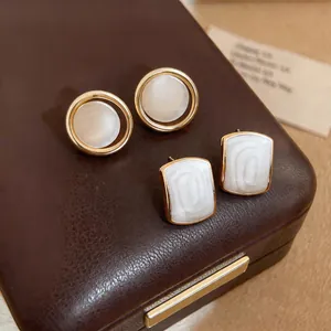 Close-up of French style geometric earrings with mother of pearl texture on brown box.