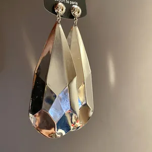 Detalle de cerca de los pendientes de gota de metal plateado facetado para mujer