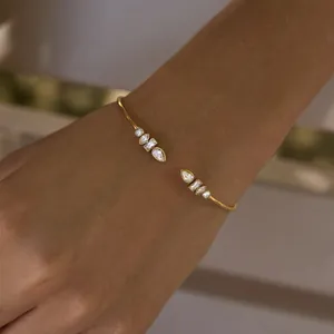 Detail of gold stainless steel cuff bracelet with sparkling marquise and round zircons