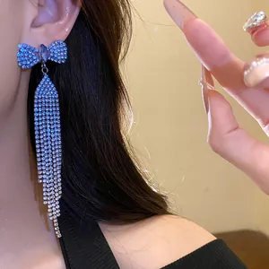 Detailed close-up of elegant blue rhinestone bow earrings with long shimmering tassels