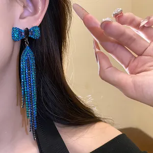 Close-up detail of elegant blue crystal bow tassel earrings worn by a female model