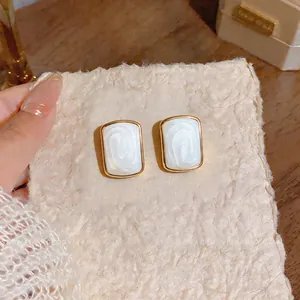 Close-up detail of French minimalist gold stud earrings with pearlescent oval inlay