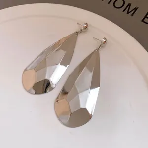 Primer plano de pendientes minimalistas de gota de agua plateada con acabado facetado