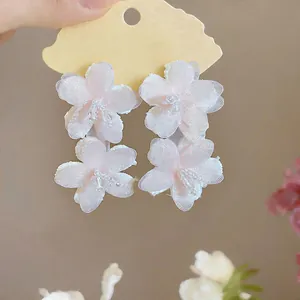Close-up of pink chiffon flower earrings with delicate white bead center details.