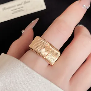 Detailed view of a wide gold geometric woven textured open ring worn on a finger