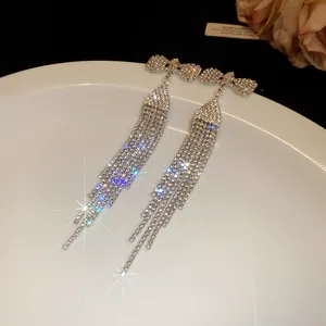 Close-up of sparkling rhinestone bow earrings with long flowing tassels