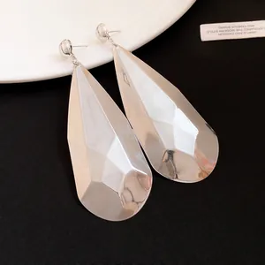 Vista detallada de pendientes colgantes de gota facetados con acabado metálico plateado
