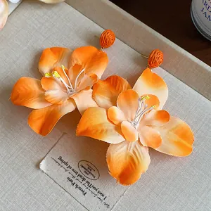 Close-up of orange raffia fabric flower earrings with delicate petal details