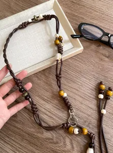 Detailed view of an ethnic beaded waist chain with brown cords and vintage wooden beads.