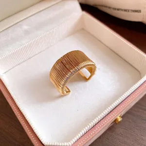 Detailed macro view of a gold woven wire open ring inside a luxury pink velvet jewelry box