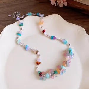 Macro detail of a colorful resin stone beaded necklace with flower charms on a plate.
