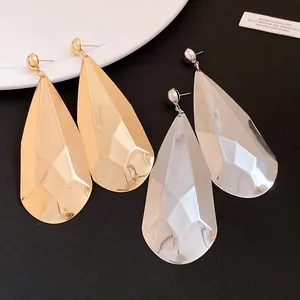 Detalle de los pendientes de gota facetados de gran tamaño en acabados oro y plata