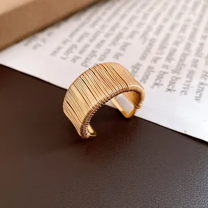 Detail of a vintage-style gold wire-wrapped open ring with a textured geometric finish.
