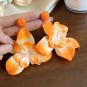 Detailed macro view of vibrant orange fabric flower stud earrings with Raffia accents