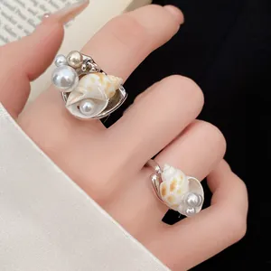 Primo piano dei dettagli di conchiglie e perle bohémien su questi eleganti anelli regolabili.