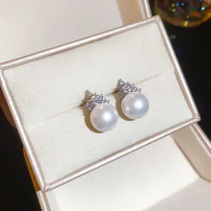 Detailed view of elegant silver needle zircon and round pearl stud earrings in a box