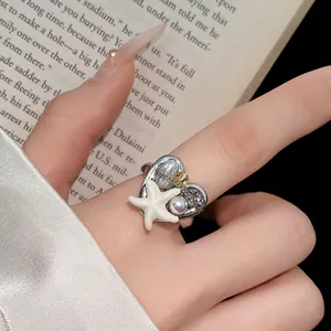 Primo piano di un anello a cuore stile boho con stella marina bianca e perle al dito