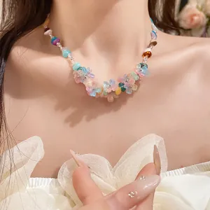 Detailed close-up of a colorful resin flower and stone beaded necklace worn on a model's neck.