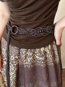 Detailed macro view of an ethnic braided waist chain with retro vintage wooden beads.