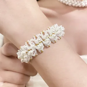 Elegant white pearl beaded necklace with intricate woven pattern and gold accents.