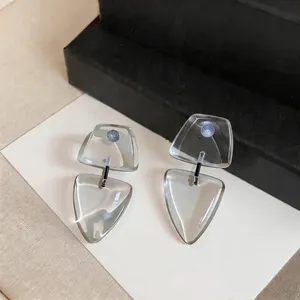 Primer plano de pendientes geométricos de resina transparente con agujas de plata