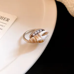 Dettaglio di un anello aperto bohémien in argento con conchiglia naturale e perle